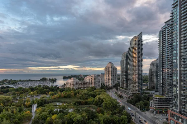 Leading Road. The photograph was shot on September 25, 2022, during dusk hours in the city of Toronto, Ontario, Canada. It was taken from the top floor of a highrise building with a view of Lakeshore blvd, park, marina, and lake Ontario.