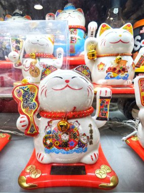 PARIS, FRANCE  OCTOBER 11, 2025: Maneki-neko is a common Japanese figurine believed to bring good luck to its owner. Made of ceramic or plastic, the figurine depicts a cat, traditionally a calico Japanese bobtail, with one paw raised.