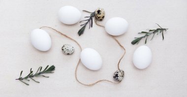 Paskalya yumurtaları, bıldırcın yumurtaları ve ışık altında ağaç dalları. Doğal keten kumaş. Masa dekorasyonu. Paskalya pastası.