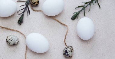 Paskalya yumurtaları, bıldırcın yumurtaları ve ışık altında ağaç dalları. Doğal keten kumaş. Masa dekorasyonu. Paskalya pastası.