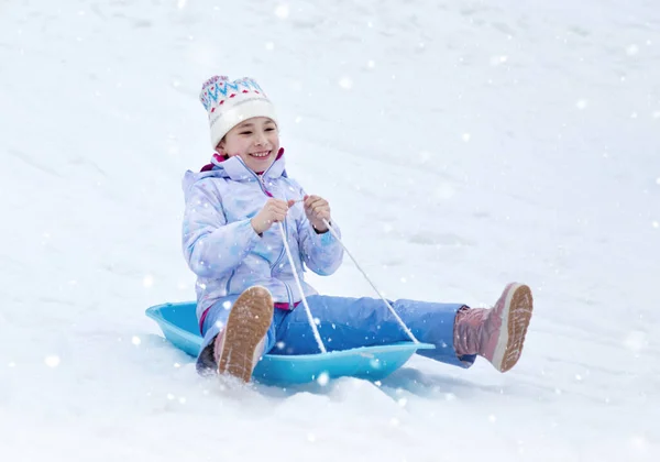 快乐的小女孩骑着雪橇从山上滑下来 童年的概念 在冬天滑行 快乐的童年 — 图库照片