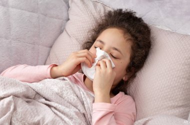 Küçük hasta kız battaniyenin altında alerjik rhinitis ile yatıyor, kendini kötü hissediyor, yüksek ateş, alerji, sümük, grip sırasında üzüntü düşüyor..