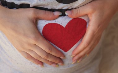 Karnında kalp olan hamile bir kadın. Yüksek kalite fotoğraf.