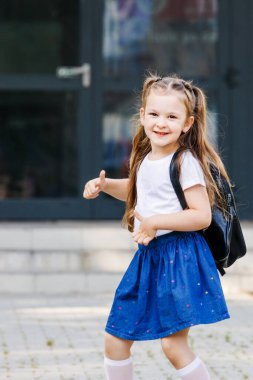 Okul, kız okulun yanında sırt çantasıyla duruyor. Öğrenme konsepti. Sırt çantalı neşeli kız okula gidiyor. Mutlu çocukluk hayalleri. Çocukluk kavramı. Mutlu aile