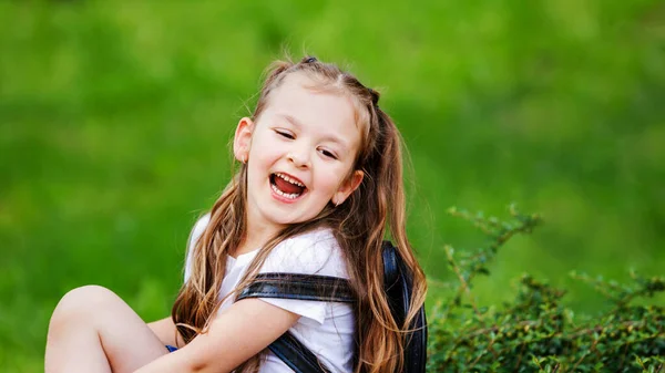 Αξιολάτρευτο Κοριτσάκι Κάθεται Στο Γρασίδι Και Γελάει Χαρούμενη Μαθήτρια Μορφωμένη — Φωτογραφία Αρχείου