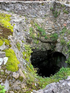 Old stone wall and green moss in the entrance of the cave. clipart