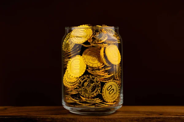 gold coin in glass bottle on black scene, money and gold saving concept