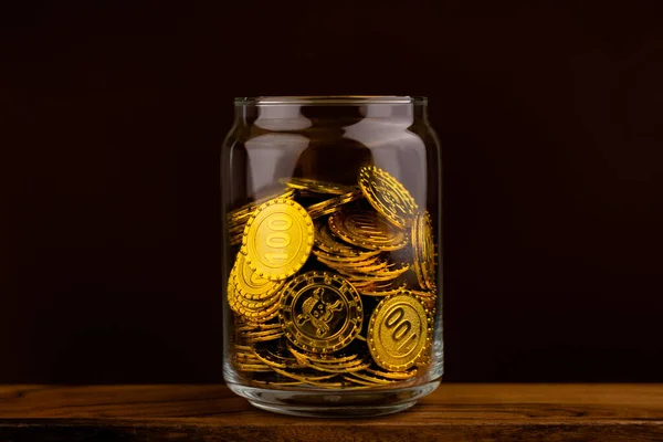 gold coin in glass bottle on black scene, money and gold saving concept