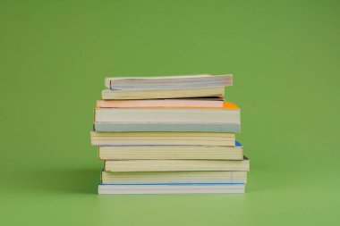 Kitaplar. Açık yeşil zemin üzerine yığılmış bir yığın kitap. Okuyorum. Okuma konsepti. ve kitap koleksiyonu