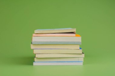 Kitaplar. Açık yeşil zemin üzerine yığılmış bir yığın kitap. Okuyorum. Okuma konsepti. ve kitap koleksiyonu