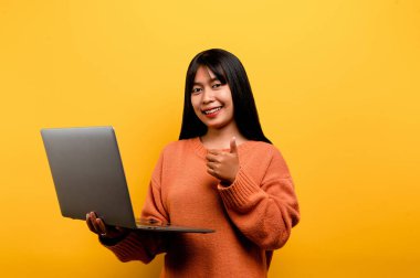 Asyalı bir kız internet üzerinden iletişim kurma kavramı. Ev sarısı stüdyo fotoğrafında dizüstü bilgisayar kullanıyor. Boş zamanlarını sosyal ağlarda, alışverişte ya da internette arkadaşlarıyla sohbet ederek geçirmekten mutlu..