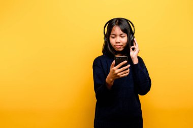 Asyalı kadın telefonu mutlu bir şekilde kullanıyor ve müzik dinliyor. Müzikle rahatlıyor. Rahat bir günde. Dans ve rahatlama konsepti. çevrimiçi müzik dinlemek