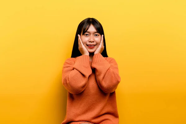 アジア系の女の子オレンジのカジュアルなドレスを着て 黄色の背景幸せな笑顔と上げ手で勝者の表情で勝利を祝います 幸せな表情 — ストック写真