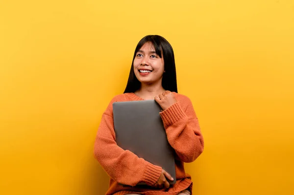 Asian woman and laptop and are happy to work Photo of a beautiful Asian woman who is happy working at home. using a laptop computer yellow studio work at home concept