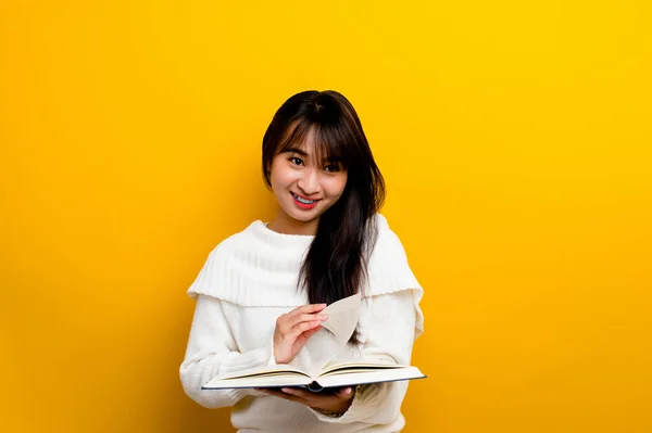 Read a book, study with the protagonist, seek knowledge, food for thought, girl reading a book and smiling. in the photo studio yellow backdrop