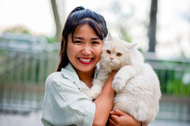 Kedilere olan aşkıyla evde oynayan bir kadın, kedisiyle olan bağında parıldayan bir gülümseme. İnsanların ve kedilerin ilişkileri, kedi sahipleri, evcil kediler, şişman kediler