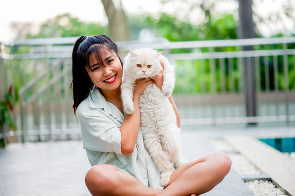 Woman holding cat playing at home with love for cats The smile glints in his bond with his fluffy pet cat. The relationship of people and cats, cat owners, domestic cats, fat cats