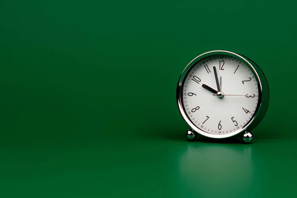 alarm clock silver white dial on green screen Working with time. Be on time. Keep time. Value time concept.