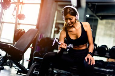 Kol egzersizleri. Kulaklık takan genç kadın egzersiz yaparken egzersiz yaparken egzersiz yapmak için egzersiz yapıyor. Egzersiz yaparken egzersiz yapıyor..