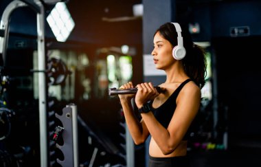 Kol egzersizleri. Kulaklık takan genç kadın egzersiz yaparken egzersiz yaparken egzersiz yapmak için egzersiz yapıyor. Egzersiz yaparken egzersiz yapıyor..