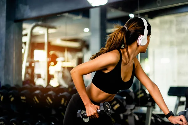 lifting dumbbells arm exercises Young woman wearing headphones while exercising Create energy for exercise with exercise music, body weight exercises for a healthy body.
