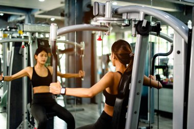 Kollarınızı bu kol egzersiz makinesiyle çalıştırın. sağlıklı kadınlar spor salonunda egzersiz yaparlar.