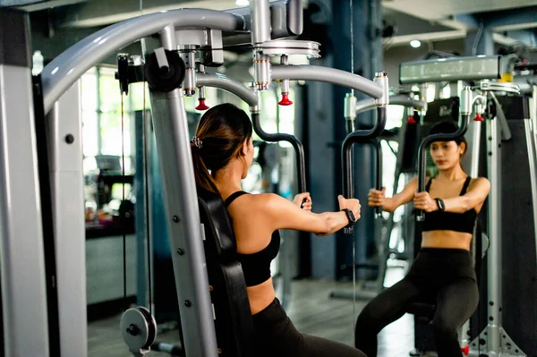 Exercise your arms with this arm exercise machine. healthy women exercise in fitness gym