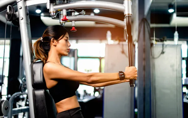 Exercise your arms with this arm exercise machine. healthy women exercise in fitness gym
