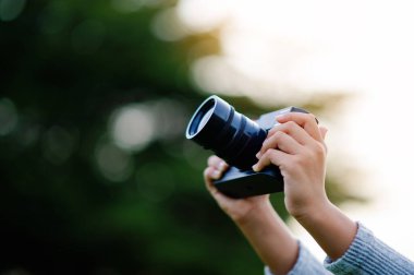 Aynasız bir kamerayla fotoğraf çek. Küçük kız doğa fotoğrafçılığı yapıyor. Küçük fotoğrafçı fotoğraf çekmenin keyfi.