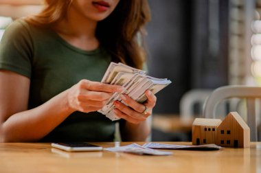 Dolar birimi Asyalı kız para, maaş, finansal yatırımlardan gelir, nakit akışı, alışveriş ve ödemeleri sayıyor.
