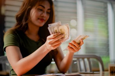 Dolar birimi Asyalı kız para, maaş, finansal yatırımlardan gelir, nakit akışı, alışveriş ve ödemeleri sayıyor.