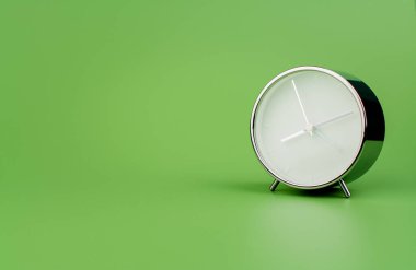 Açık yeşil zemin üzerinde beyaz, modern çalar saat. Zaman kavramı ve değerli zamanla çalışma