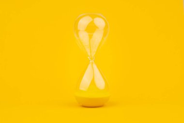 Sarı arkaplan üzerindeki kum saati, zaman ve geri sayım sınırı, son teslim tarihleri ve atamaları karşılamak için acil iş.