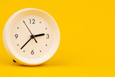 Sarı arka plandaki saat, zamanla ve planlama hayatıyla çalışmak, stüdyo fotoğrafı.