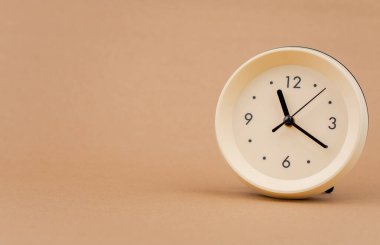 Açık kahverengi arka plan stüdyosundaki çalar saat fotoğrafçılığı zaman, yaşam ve çalışma kavramı.