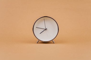 Açık kahverengi arka plan stüdyosundaki çalar saat fotoğrafçılığı zaman, yaşam ve çalışma kavramı.