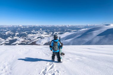 Dağın tepesinde elinde snowboardla snowboardcu. Kış serbest kayak sporu