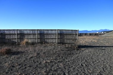 Sand fences made of bamboo installed on a sandy beach in Japan. The purpose of the sand fence is to prevent sediment on the road caused by blown sand. clipart