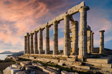 Sounion, Attica - Greece. The Temple of Poseidon at cape Sounion. Colorful sunset with beautiful cloudy sky. Golden hour