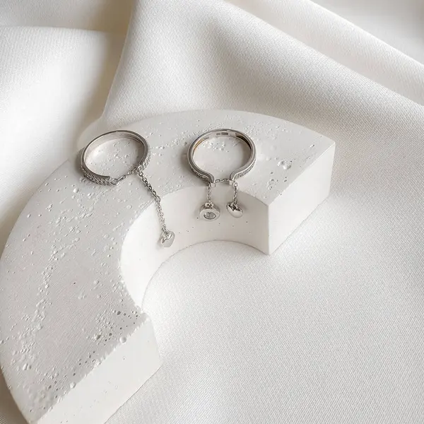 Zincirli kalp şeklinde kolyeleri olan saf gümüş yüzükler..