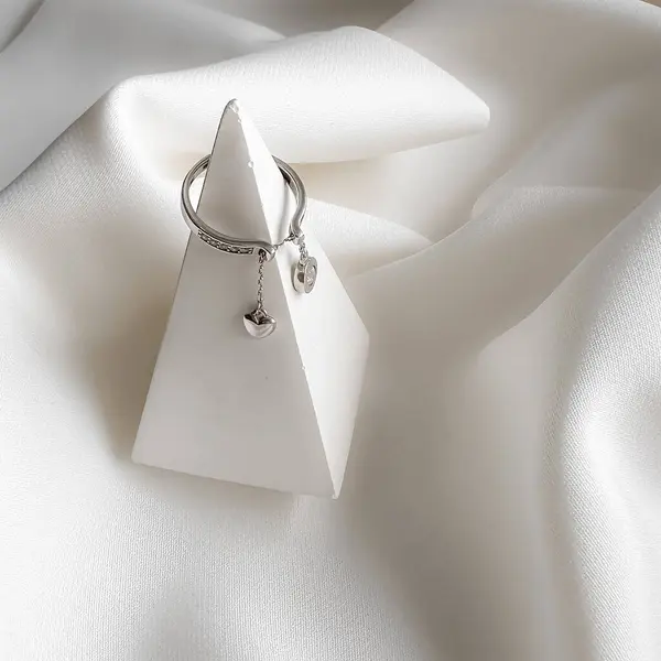 Zincirinde kalp şeklinde bir kolyesi olan saf gümüş bir yüzük..