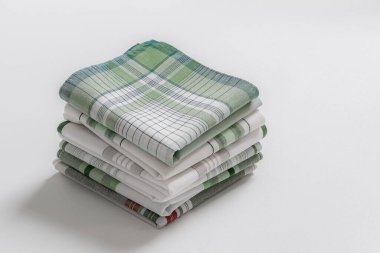 Beyaz arka planda yeşil çizgili ve ekose desenli temiz, katlanmış erkek mendilleri yığını.