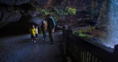 Heyecanlı bir aile, Dry Falls şelalesinde eğlenen turistler, Kuzey Carolina 'daki Nantahala Ulusal Ormanı' nda turistik bir eğlence. Appalachian dağlarındaki doğal şelalenin arkasında bir patika.