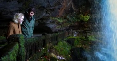 Turistler, Kuzey Carolina 'daki Nantahala Ulusal Ormanı' ndaki Dry Falls şelalesinin arkasındaki manzaranın tadını çıkarıyorlar. Appalachian dağlarındaki doğal şelalenin arkasında bir patika.