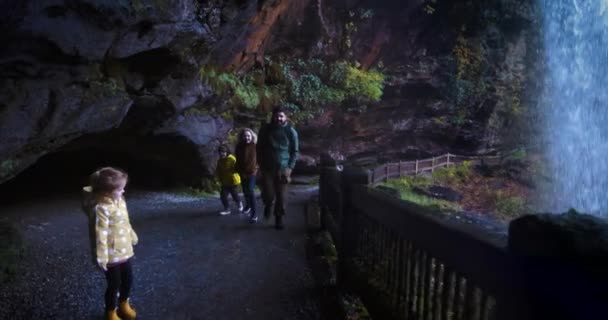 興奮した家族 ドライフォールズで楽しんでいる観光客 ノースカロライナ州のナンタハラ国立の森の観光名所 アパラチア山脈の自然の滝の後ろの歩道 — ストック動画