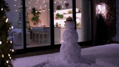 Kardan adam ve verandada pofuduk kar ile Noel tatili için dekore edilmiş modern bir daire.
