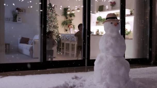 冬の夜に屋外に降る雪の結晶を見てかわいい子供たち 居心地の良い クリスマス休暇に装飾されたアパート — ストック動画