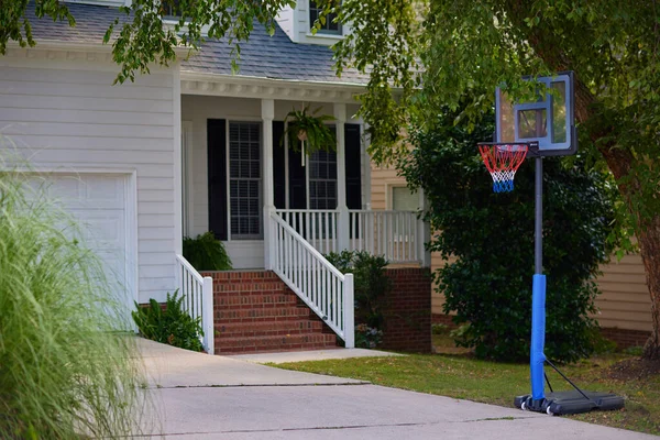 Tragbare Basketballkörbe Stehen Auf Einer Einfahrt Vor Einem Haus Familiensport lizenzfreie Stockbilder