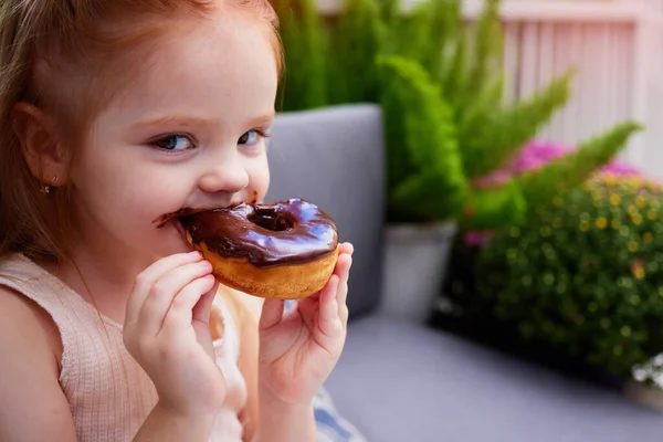 Niedliches Kleines Mädchen Kind Das Den Schokolade Glasierten Donut Isst lizenzfreie Stockfotos