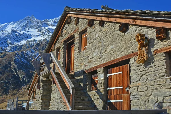 Stone house in the mountains with mountain spirit carved from wood on the walls. In the southern Swiss Alps